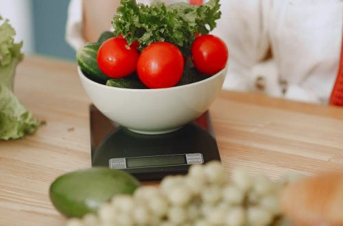 Colorful fresh vegetables including tomatoes and cucumbers on a kitchen scale for healthy eating.